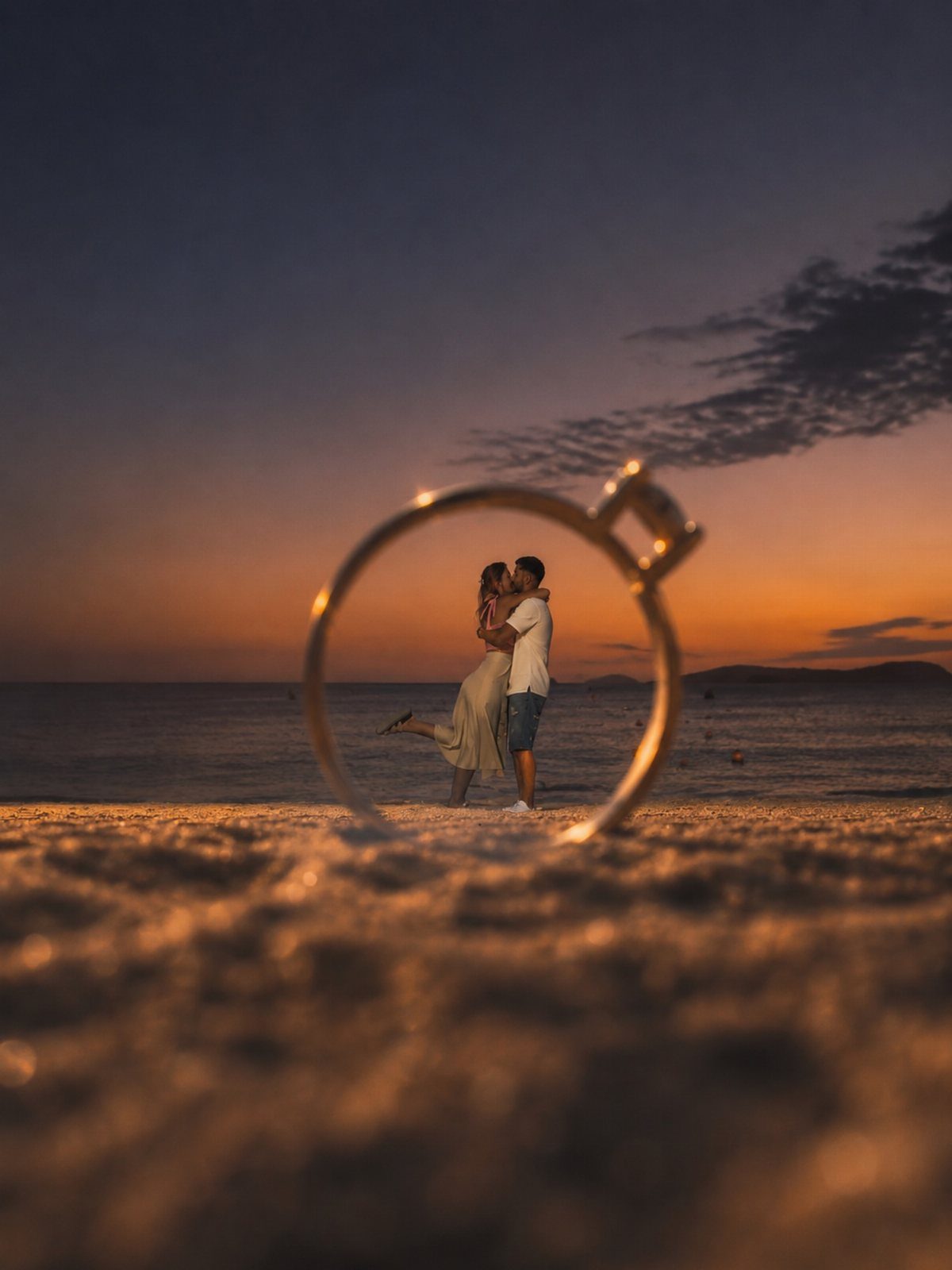 Couple kissing on a beach at sunset framed by a large gold ring