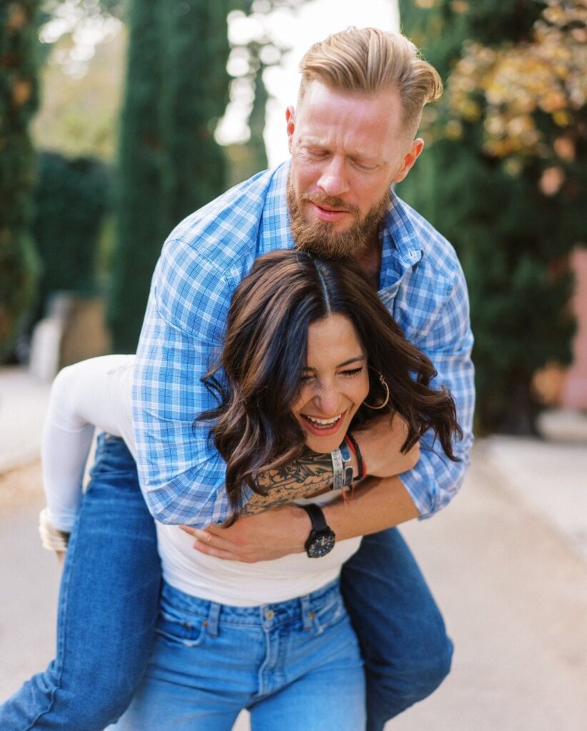 Man giving a woman a piggyback ride while smiling in an outdoor setting