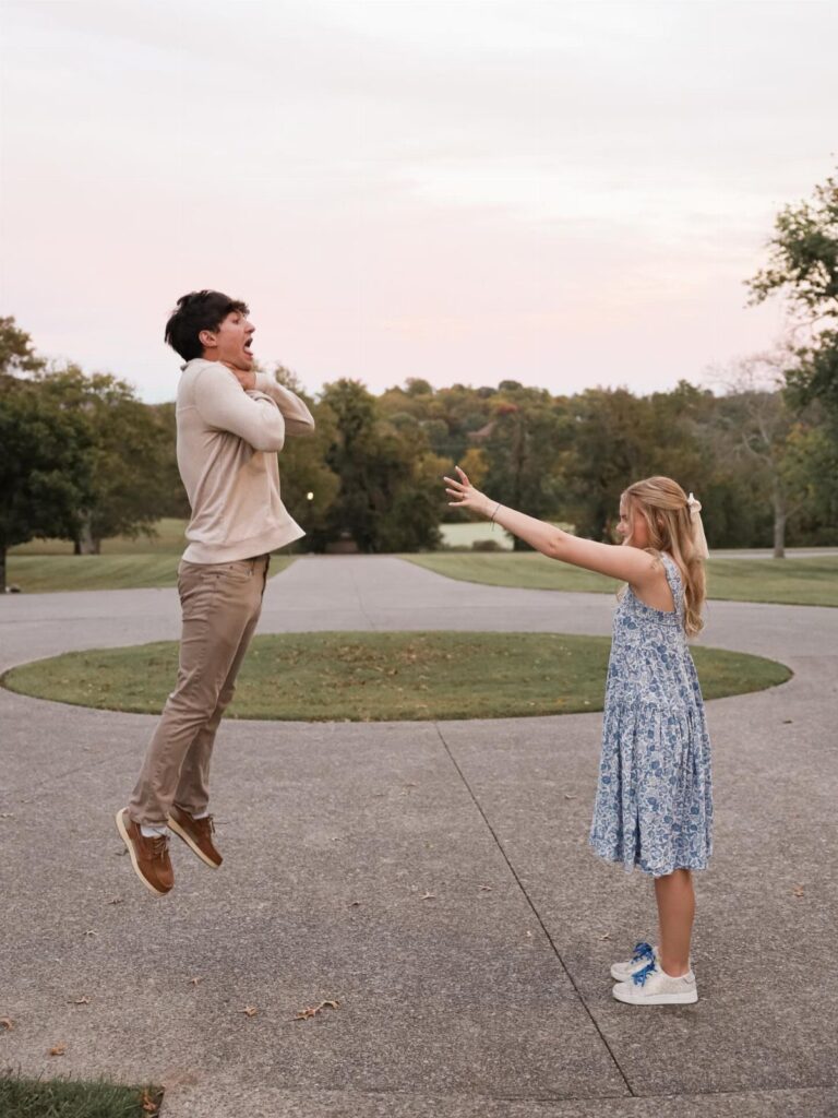 Surprised man jumping in the air while a woman reaches out toward him outdoors.