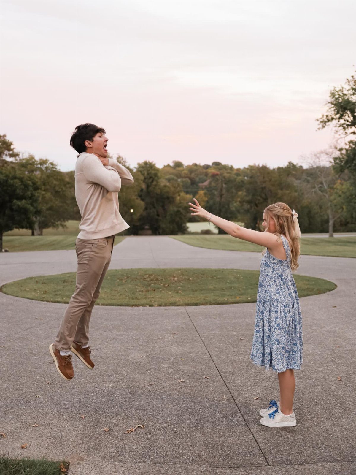Surprised man jumping in the air while a woman reaches out toward him outdoors.