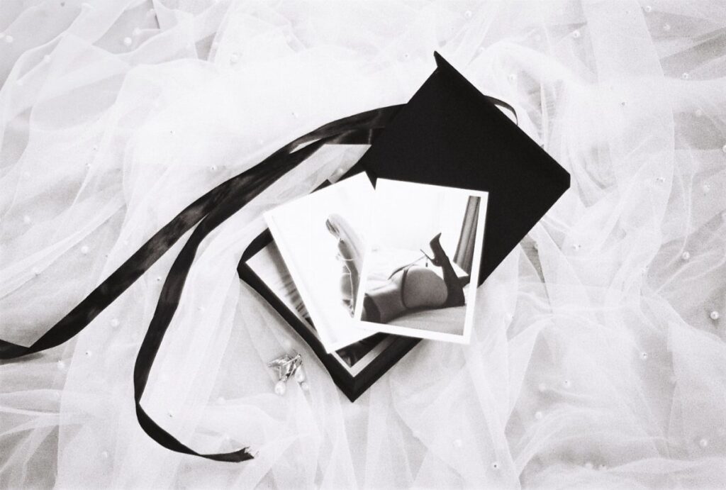 Boudoir polaroid photos resting on a black box over white bridal tulle fabric